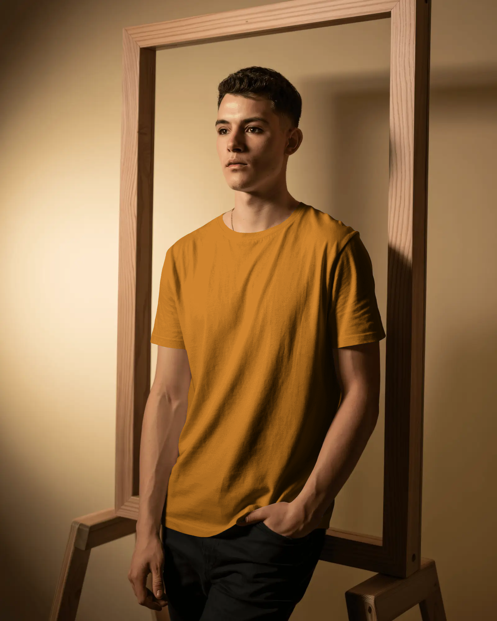 wooden-frame-studio-tshirt-mockup-male-model-posing-confident-look-warm-lighting-modern-style-2596(1)